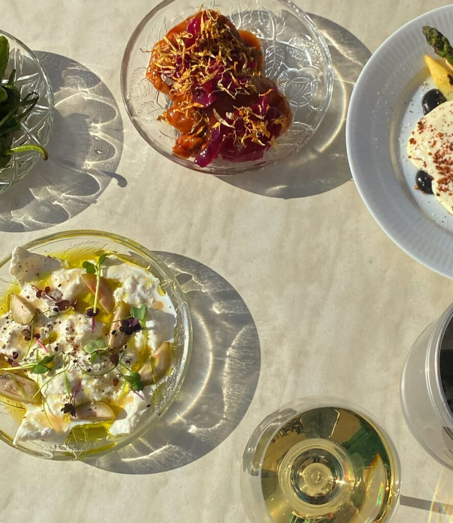 “Deleretter på små tallerkener. Burrata med syltede beder. Arancini med syltede rødløg. Et glas hvidvin.”